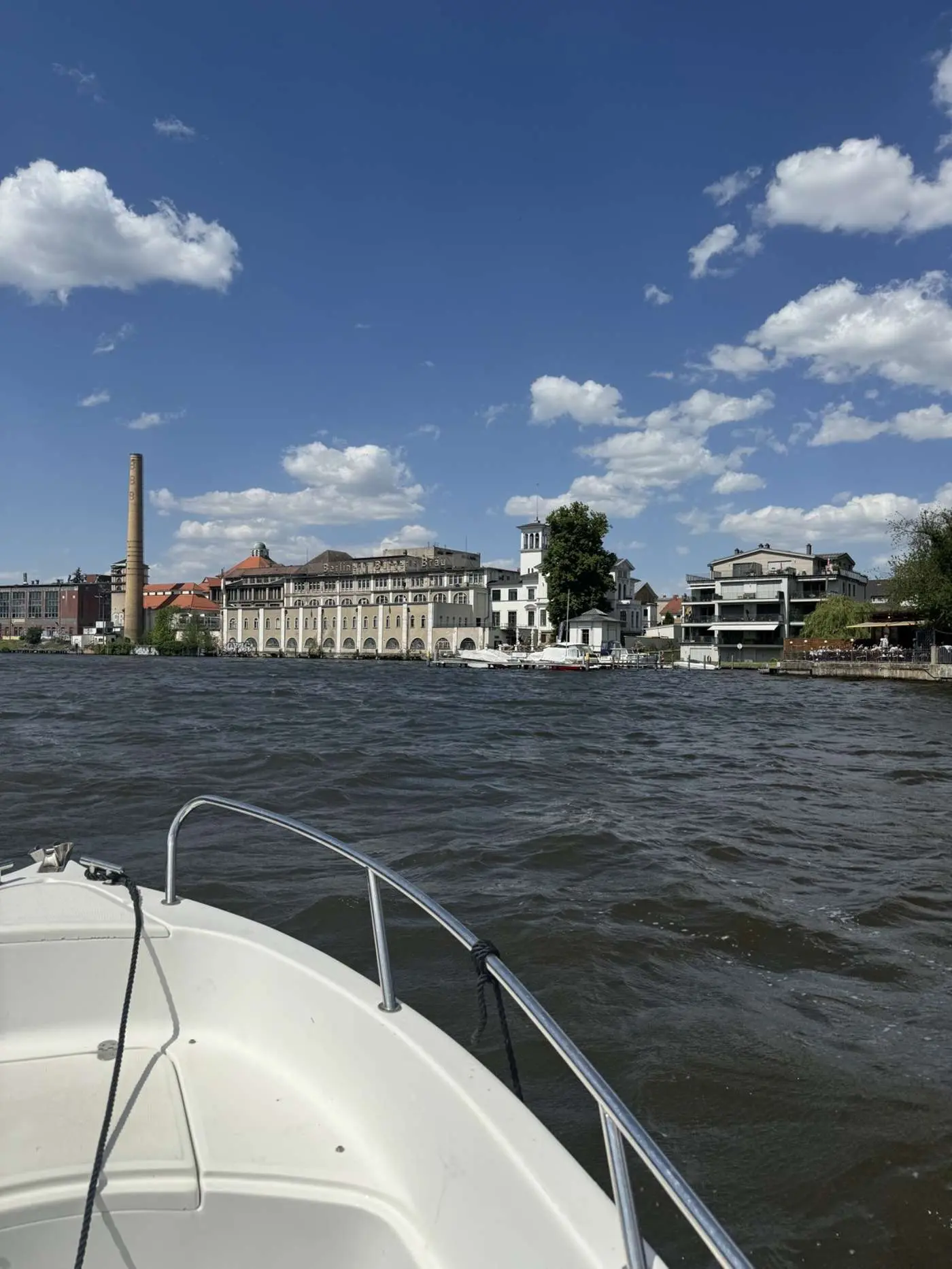 Blick vom Boot auf die Wasserlage rund um Friedrichshagen am Müggelsee mit historischer Architektur, moderner Wohnbebauung und Berliner Bürgerbräu bei sonnigem Himmel.