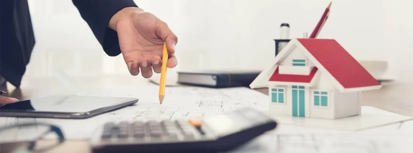 Schreibtisch mit Modellhaus, Taschenrechner und Dokumenten